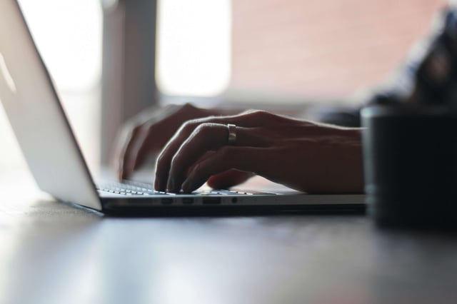 Upclose shot of someone’s hands completing a board review on laptop (1)